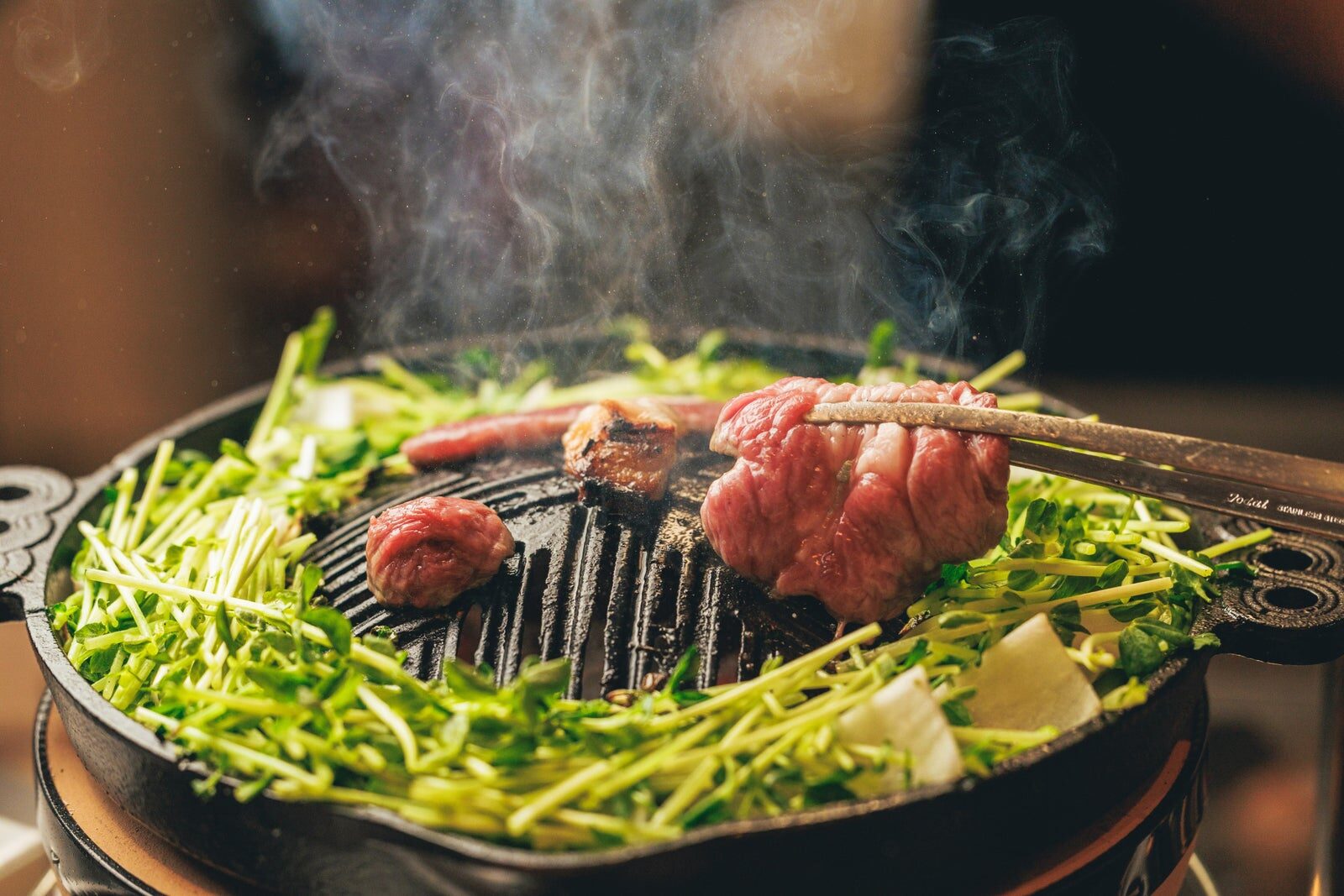 鉄鍋で焼かれる北海道直送の生ラムと豆苗